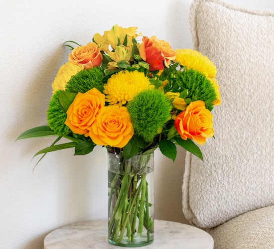 Vibrant yellow and orange flower bouquet in a glass vase, perfect for brightening any room.