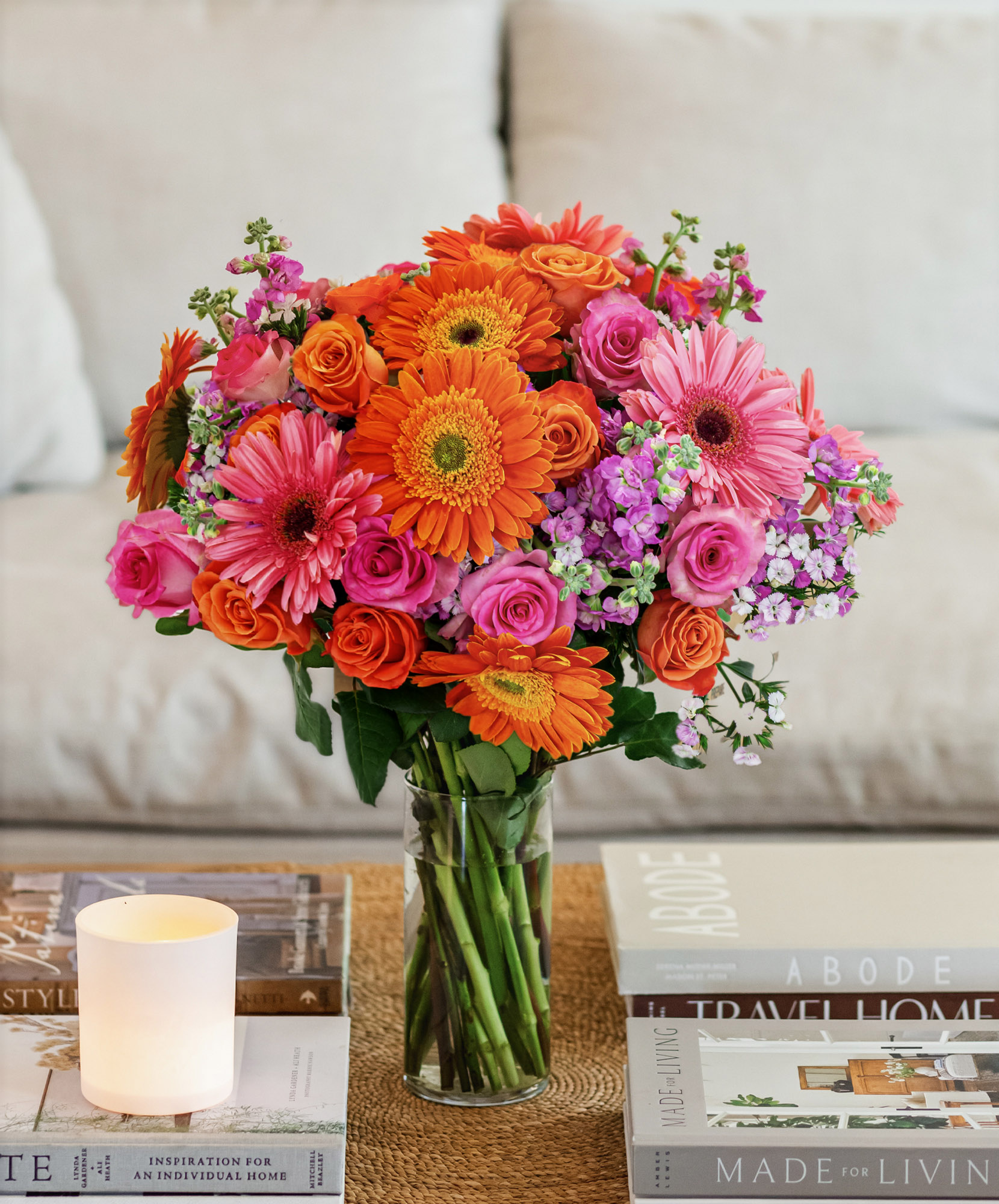Vibrant bouquet of orange gerbera daisies and pink roses in a stylish glass vase.