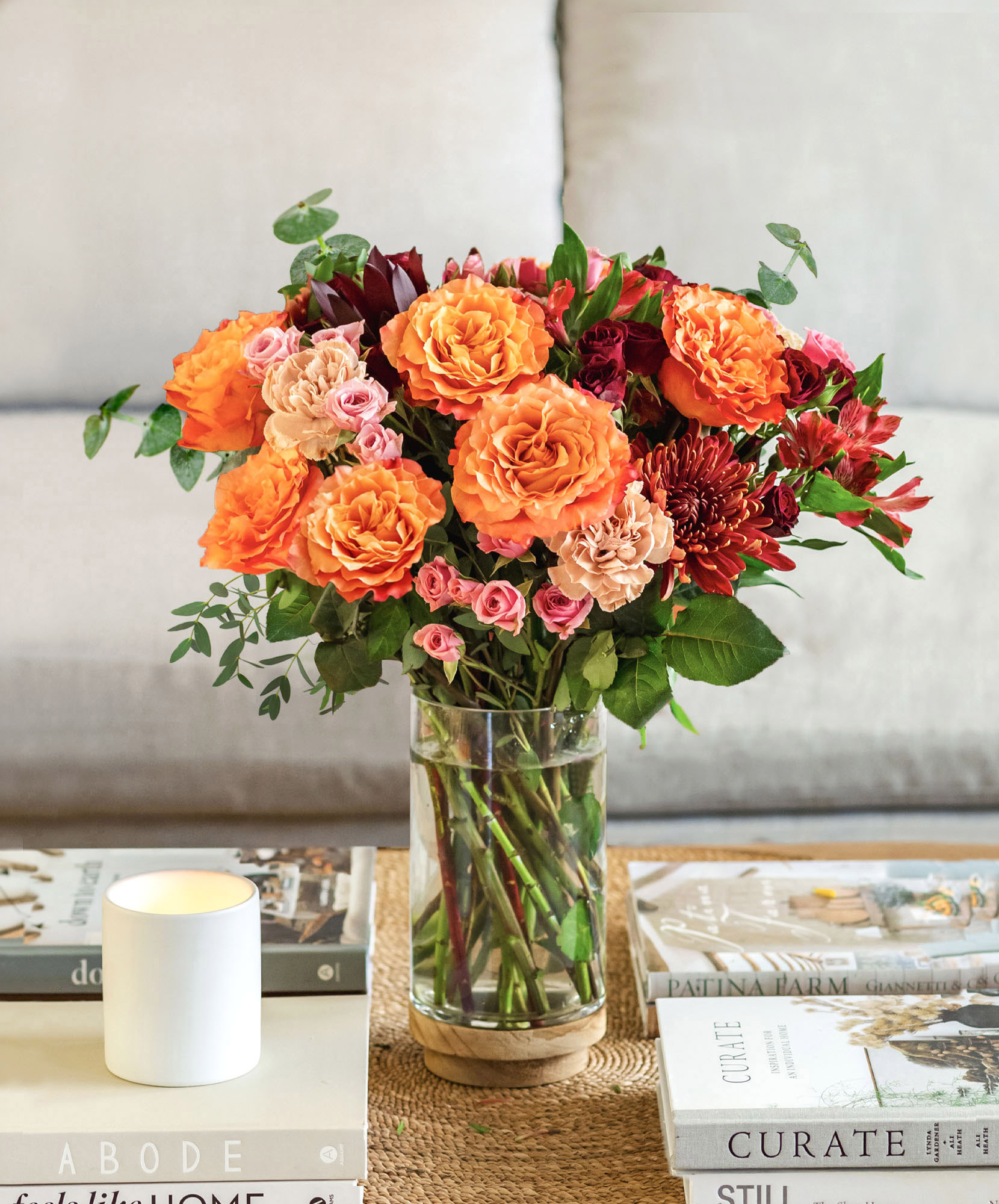 Vibrant floral arrangement featuring orange and pink roses in a stylish glass vase.