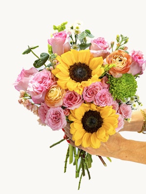Vibrant bouquet featuring sunflowers, pink roses, and lush greenery, ideal for celebrations.