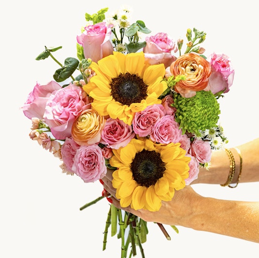 Vibrant bouquet featuring sunflowers, pink roses, and lush greenery, ideal for celebrations.