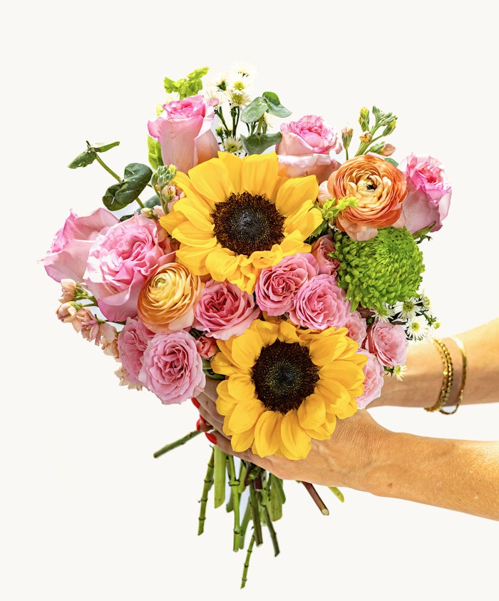 Vibrant bouquet featuring sunflowers, pink roses, and lush greenery, ideal for celebrations.