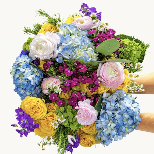 Vibrant floral bouquet featuring blue hydrangeas, pink ranunculus, and yellow roses.