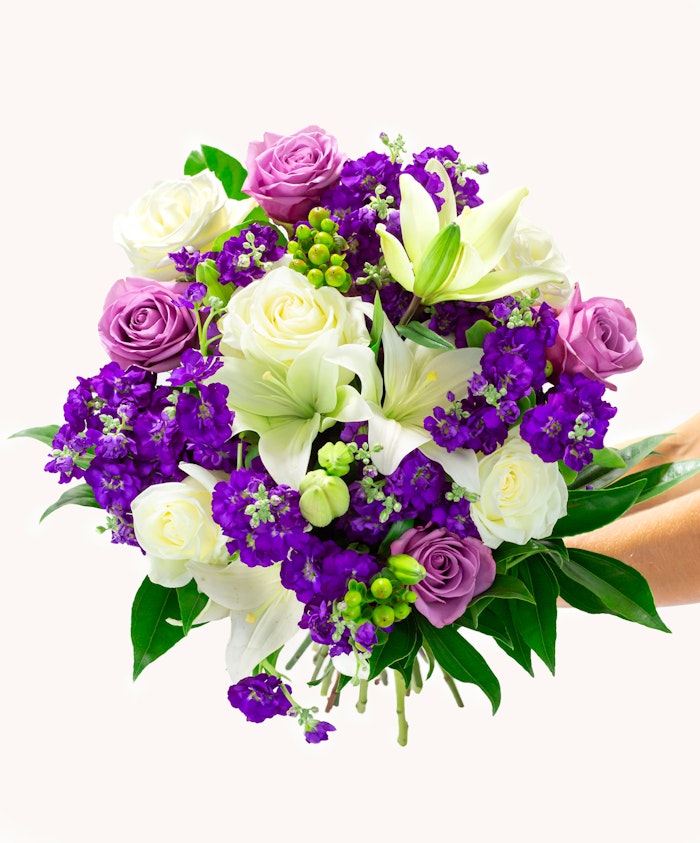 Vibrant floral bouquet featuring white lilies, purple and lavender roses, and lush greenery.