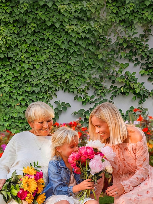 A joyful family moment with three generations enjoying colorful flowers together.