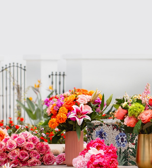 Vibrant floral arrangement featuring pink roses, lilies, and colorful blooms in stylish vases.
