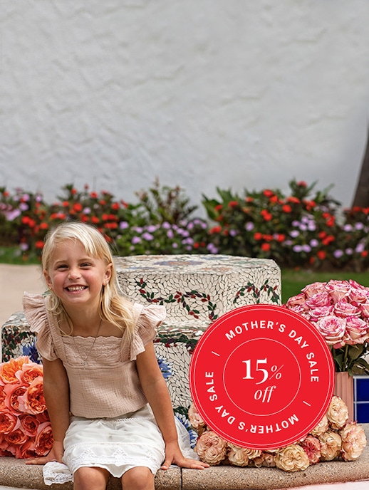 A cheerful girl sitting among vibrant roses, promoting a Mother's Day sale with a 15% discount.