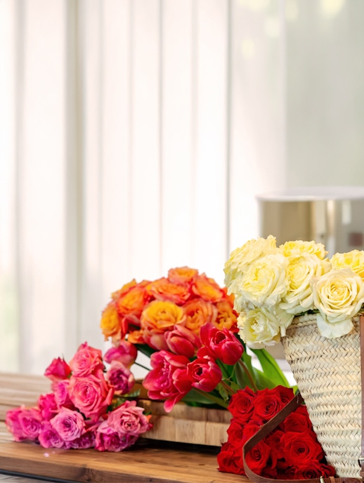 Vibrant bouquet featuring yellow roses, red tulips, and pink blooms in a rustic basket.
