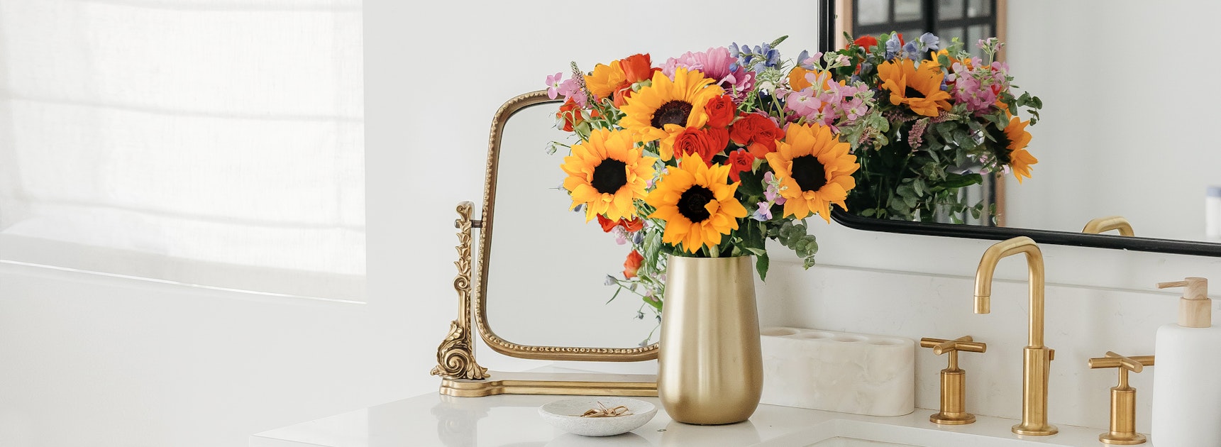 A vibrant sunflower and mixed flower arrangement on a chic bathroom counter.