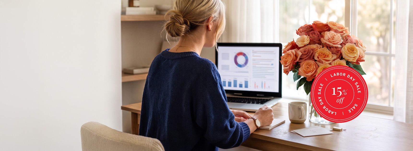 A woman working at a desk with a vibrant rose bouquet, promoting a Labor Day sale.