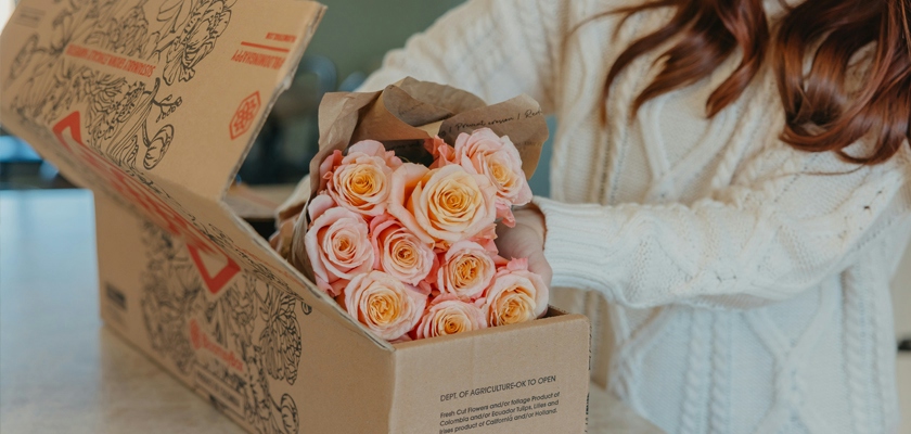 A woman unboxing a beautiful bouquet of pastel-hued roses, ready to brighten any space.