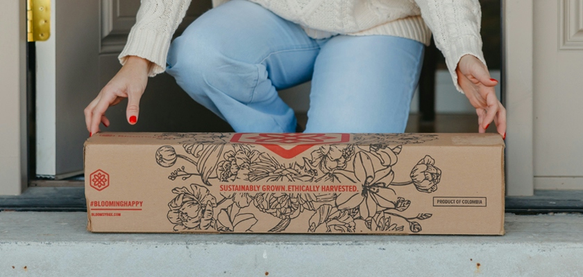 A beautifully designed flower delivery box placed on a doorstep, showcasing floral artwork.