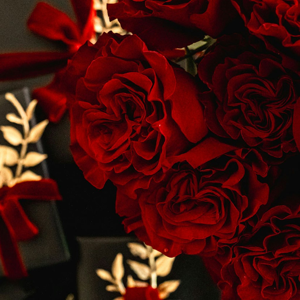 Luxurious deep red roses elegantly arranged with gift boxes for special occasions.
