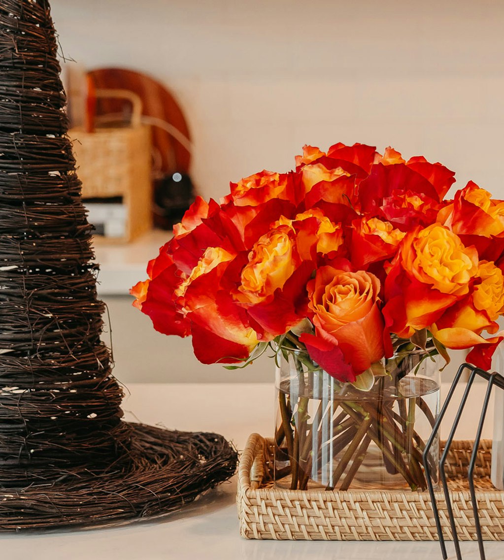 Vibrant orange and red rose bouquet in a clear vase, perfect for festive occasions.