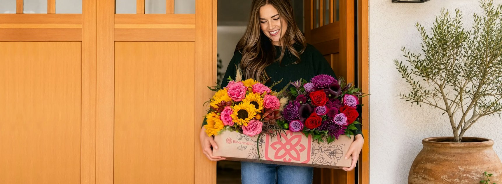 Woman holding a BloomsyBox full of sunflowers, roses and dahlias
