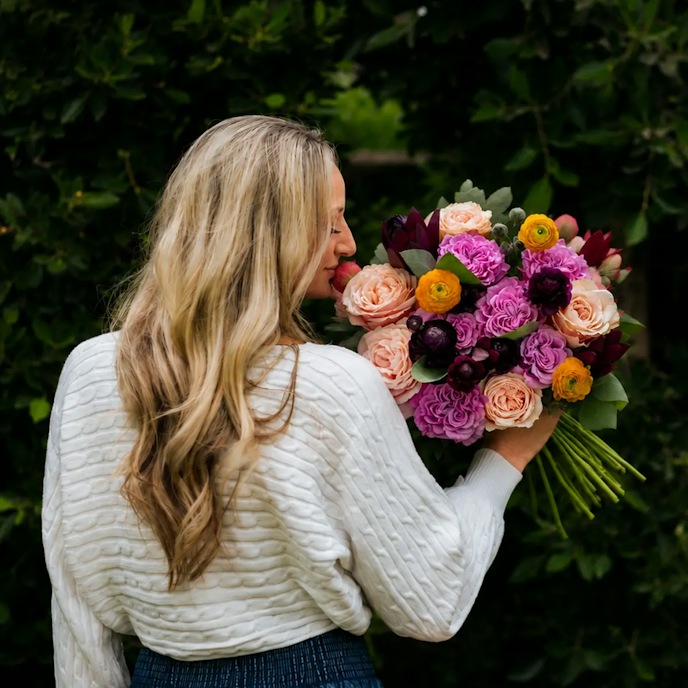 Woman smelling a bouquet of garden roses and ranunculus
