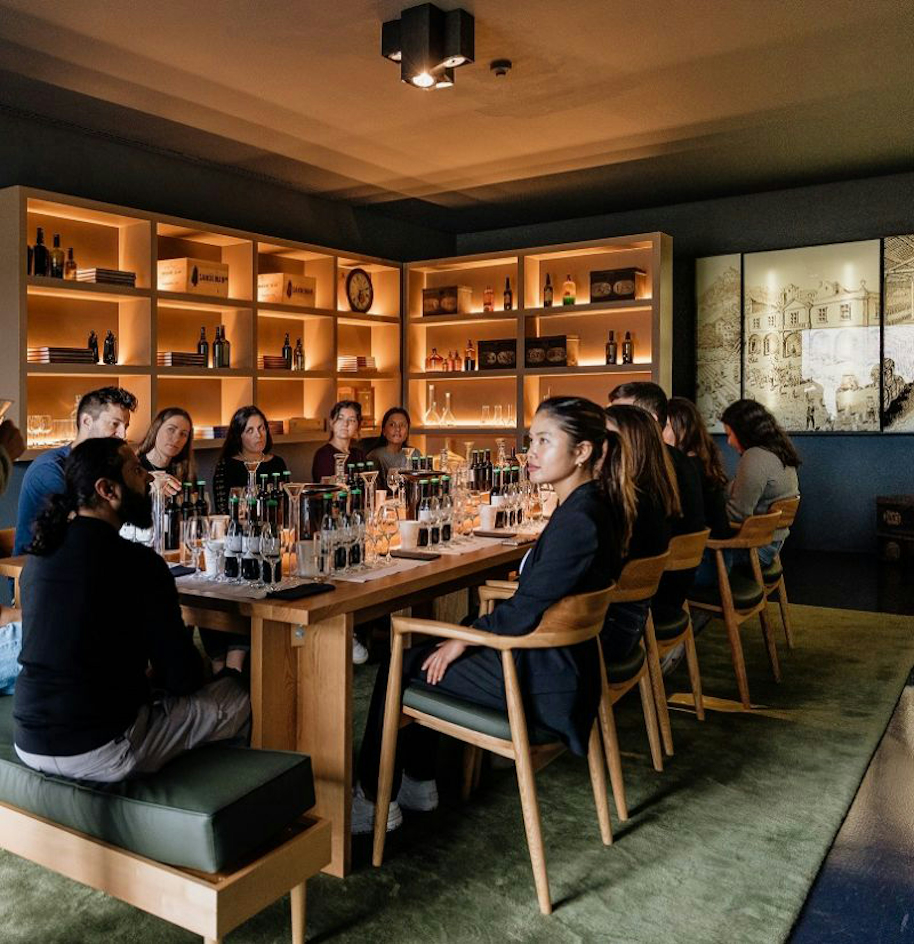 Um grupo de pessoas participa numa prova de vinhos organizada à volta de uma mesa comprida