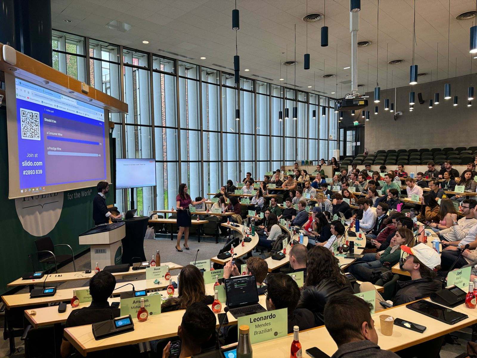 Uma grande audiência assiste a uma apresentação numa sala de aula ou conferência moderna com um ecrã projetado