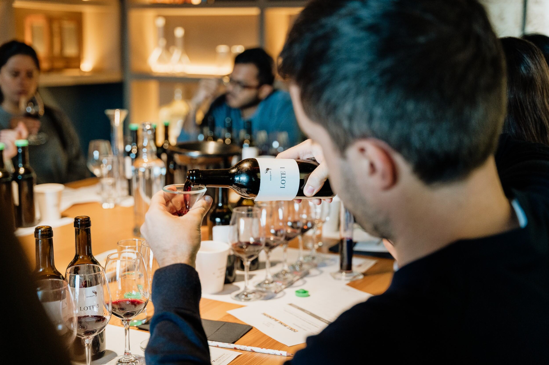Um homem serve vinho tinto de uma garrafa para uma taça durante uma prova