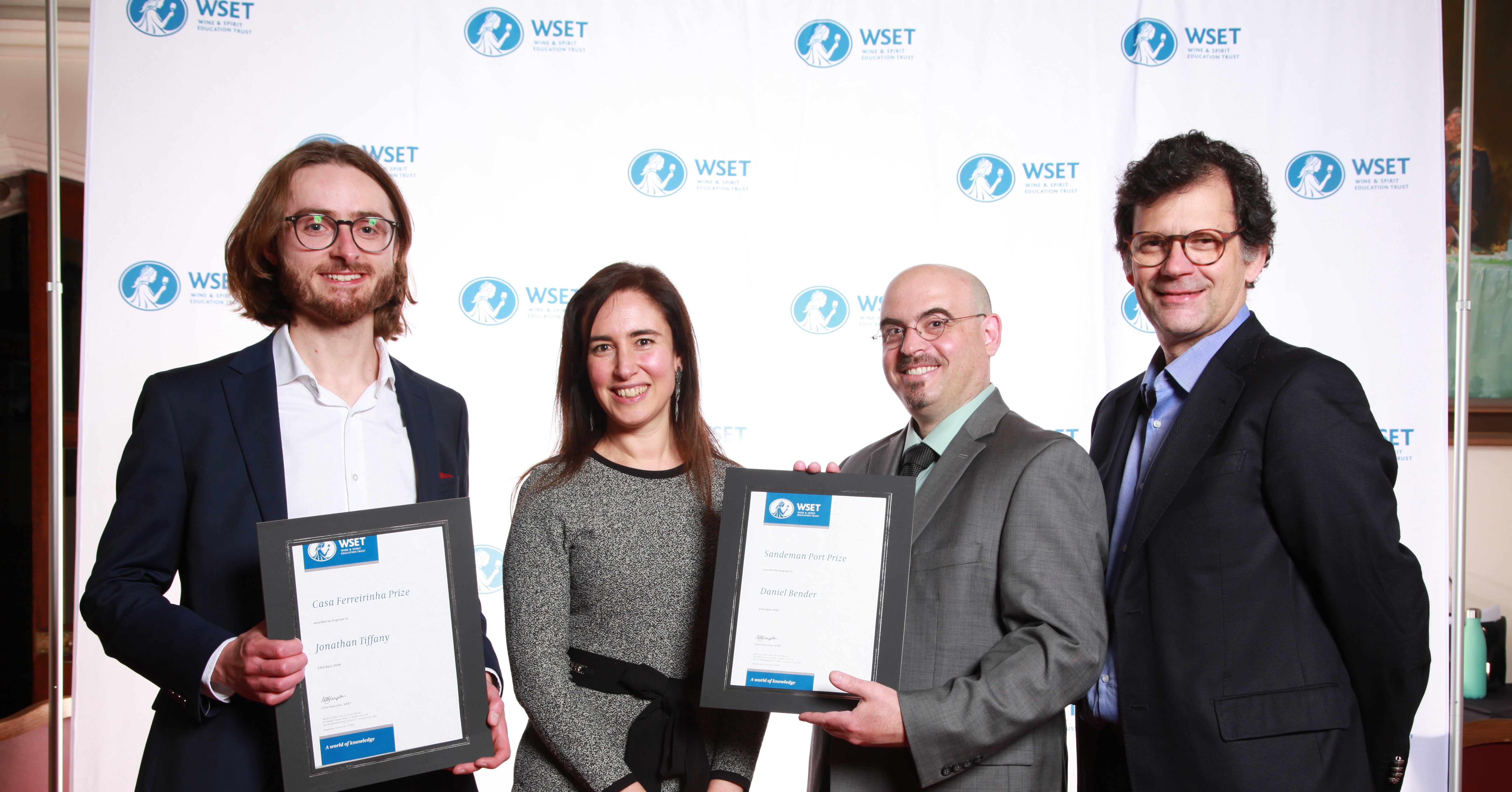 Quatro pessoas sorridentes posam com certificados de prémios da WSET, provavelmente numa cerimónia de premiação