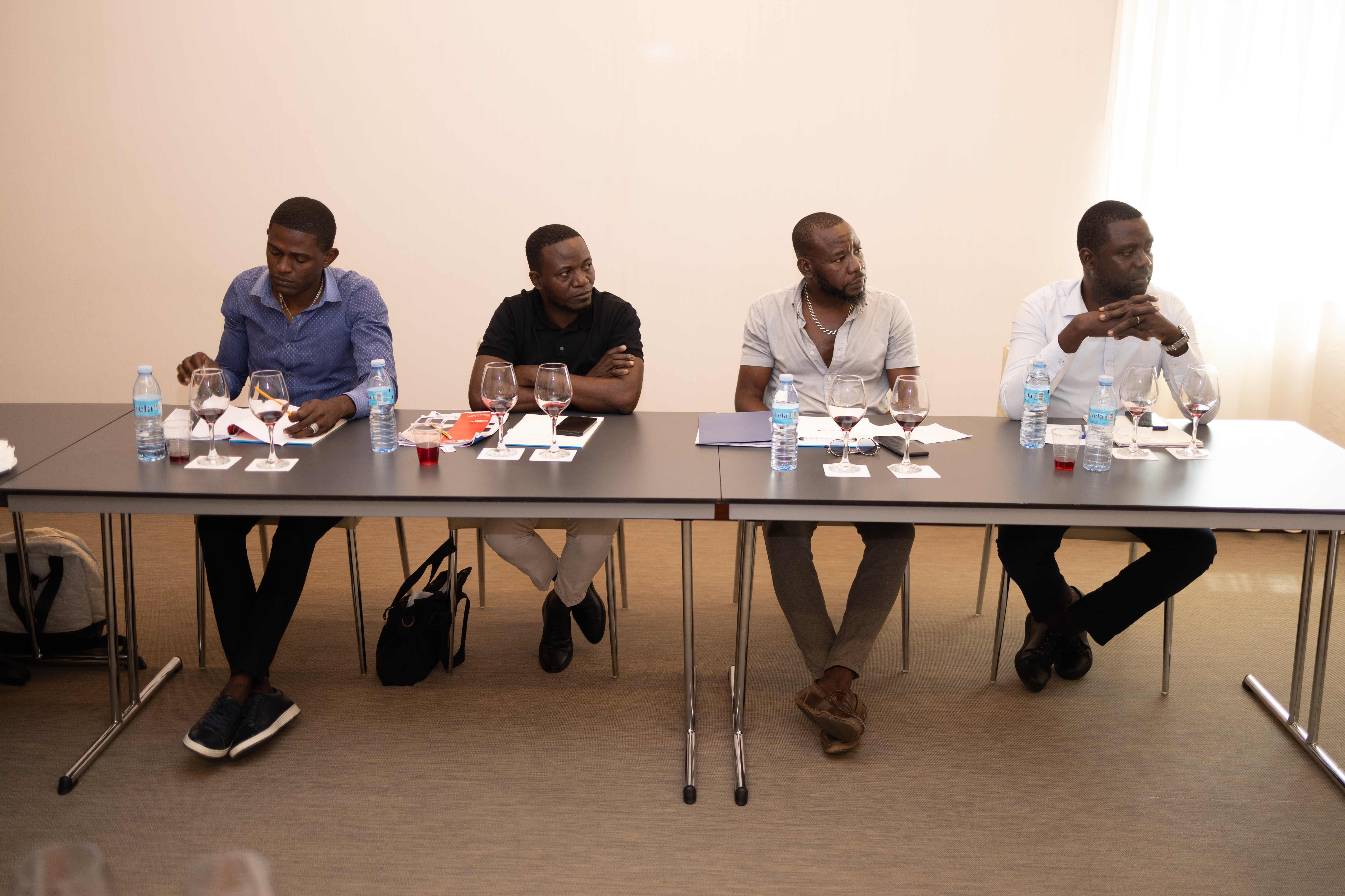Quatro homens de origem africana estão sentados numa mesa, aparentemente num evento ou reunião