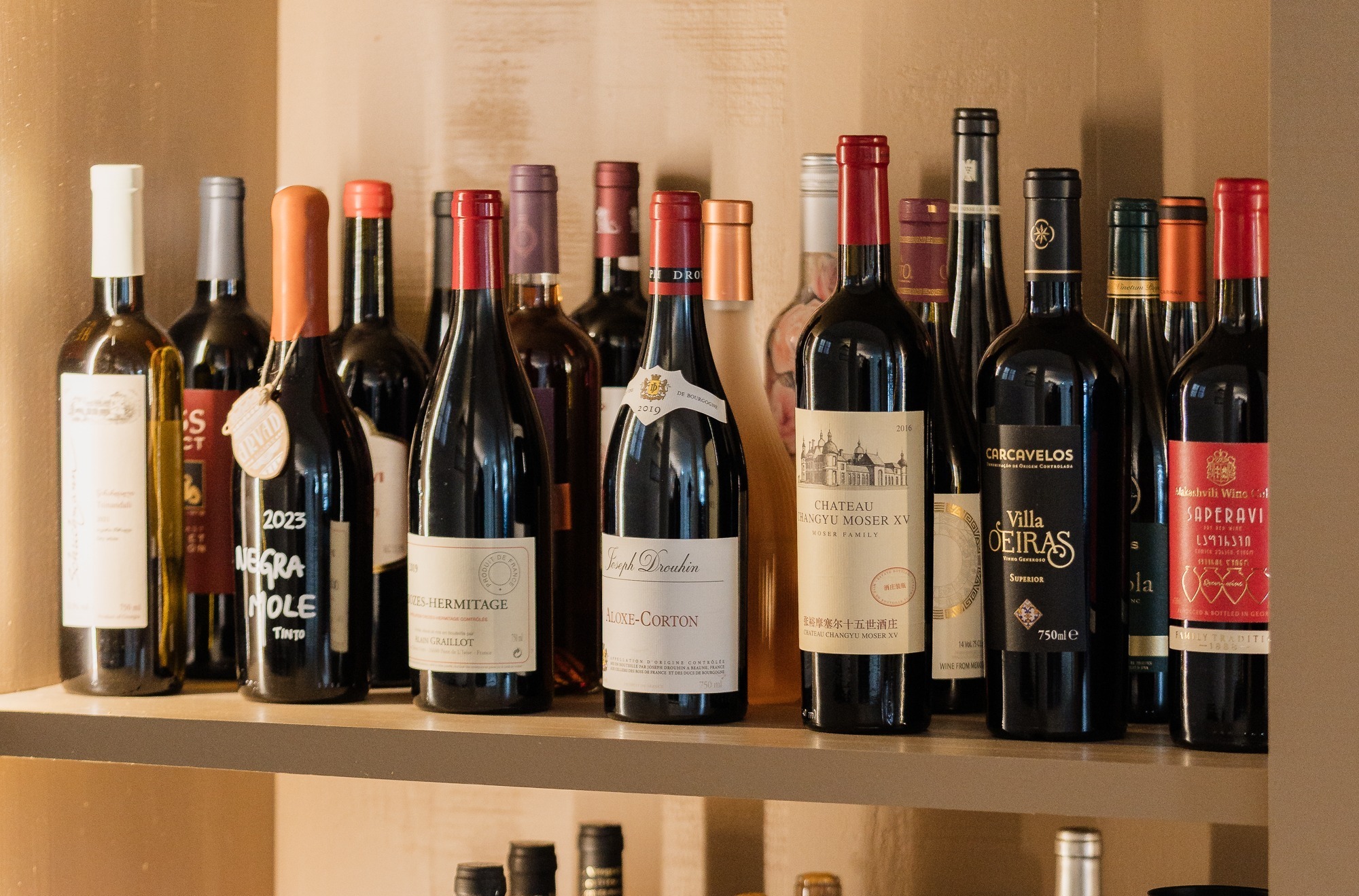 Uma estante com várias prateleiras cheias de diferentes garrafas de vinho