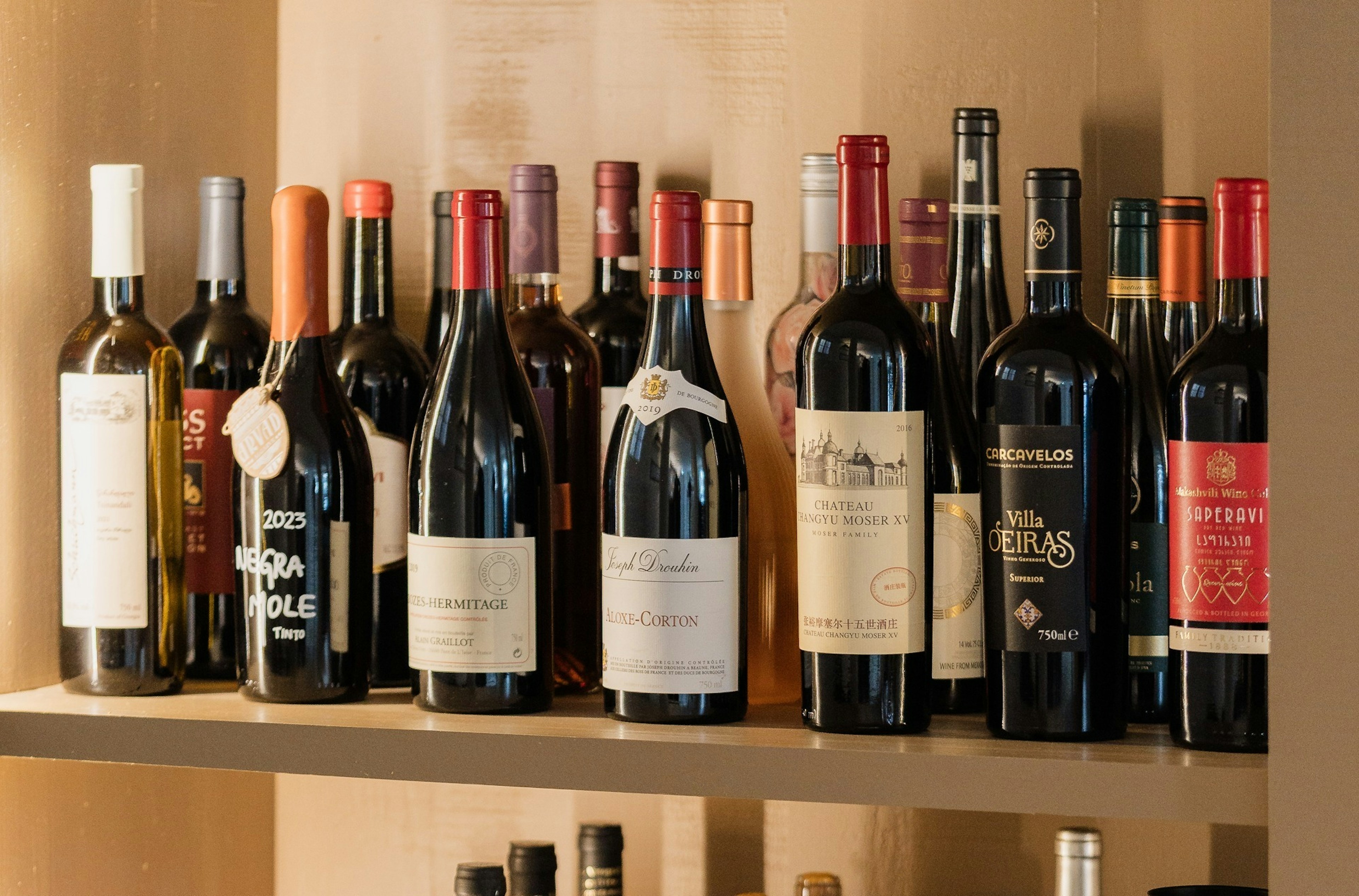 Uma estante com várias prateleiras cheias de diferentes garrafas de vinho