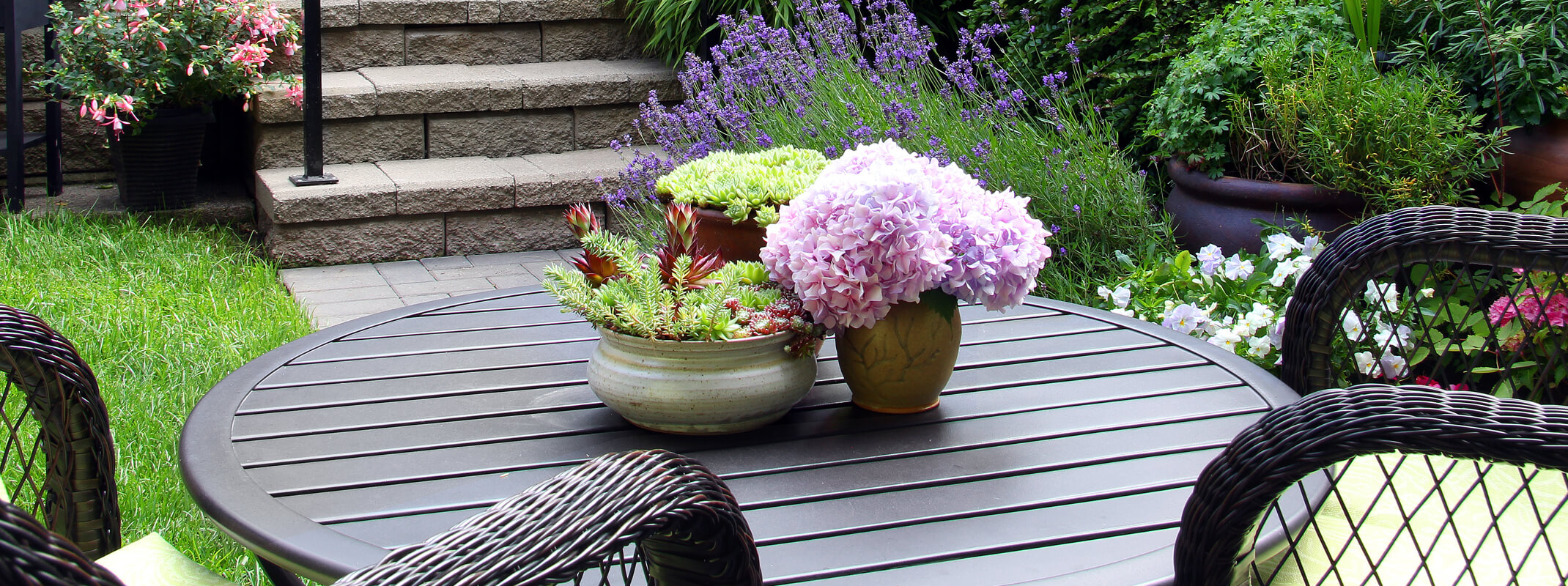 Beautiful patio with black table hydrangeas sitting on top and scented perennials growing and blooming all around