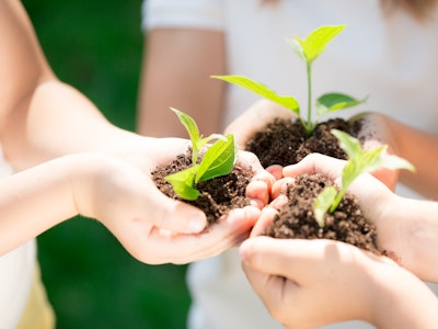 children holding dirt with plants in them in front of them