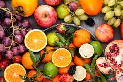 A variety of citrus fruits and berries on a table and in a platter