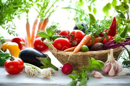 An assortment of summer vegetables on a table and in a basket