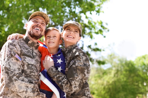 Military mom and dad in camo with son wrapped in a flag