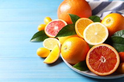 A variety of citrus fruits on a plate on a light blue wooden table