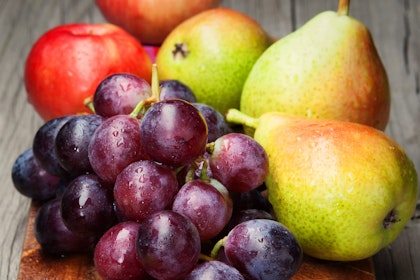 Close up of grapes, pears and apples on a wooden cutting board