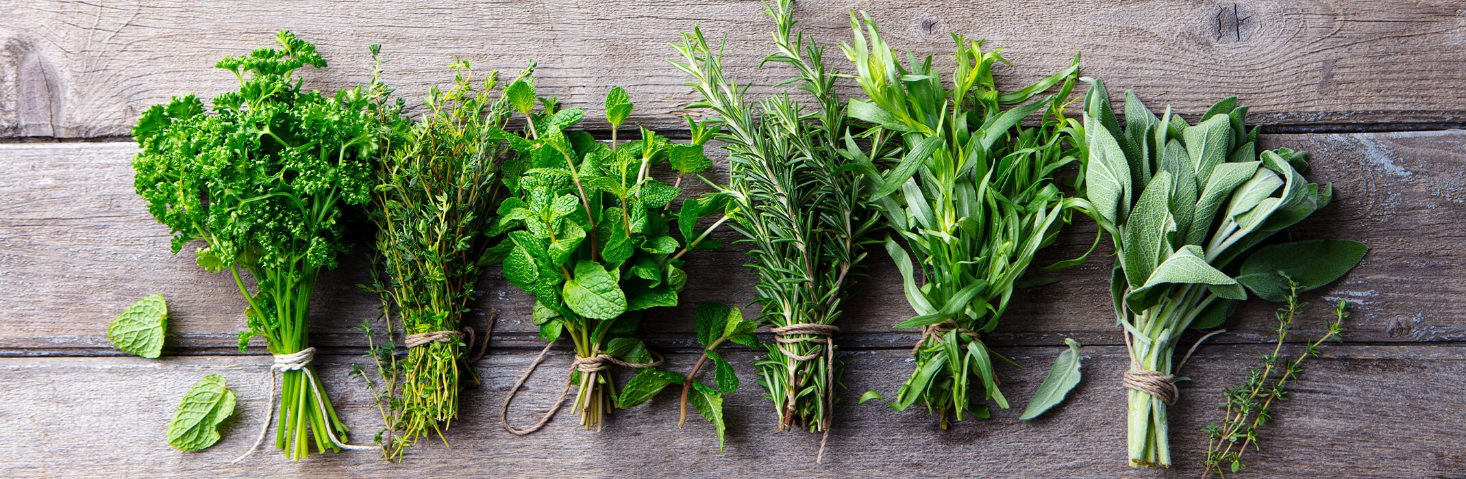 6 bunches of different herbs on a wooden table