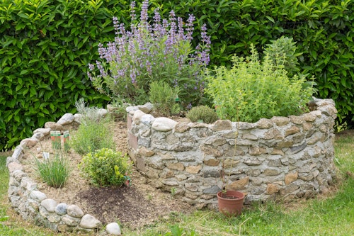 A circular raised herb garden made with stones