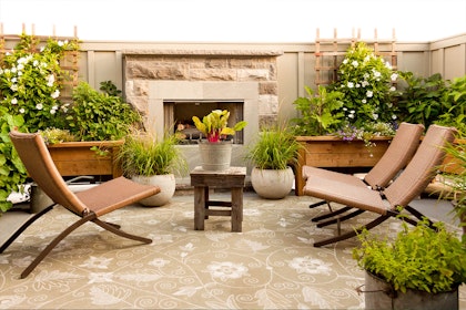 A patio with an outdoor rug and fireplace, seating and a wide variety of potted plants and flowers