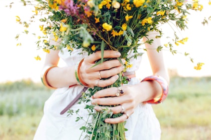 A closeup of a woman in a white dress holding a bouquet of wildflowers