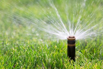 A nice lawn being watered by a sprinkler