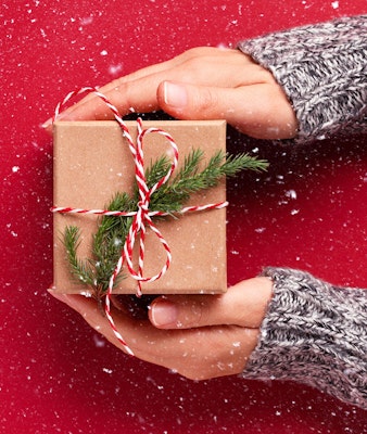 holiday package tied with red and white twine and sprig of evergreen