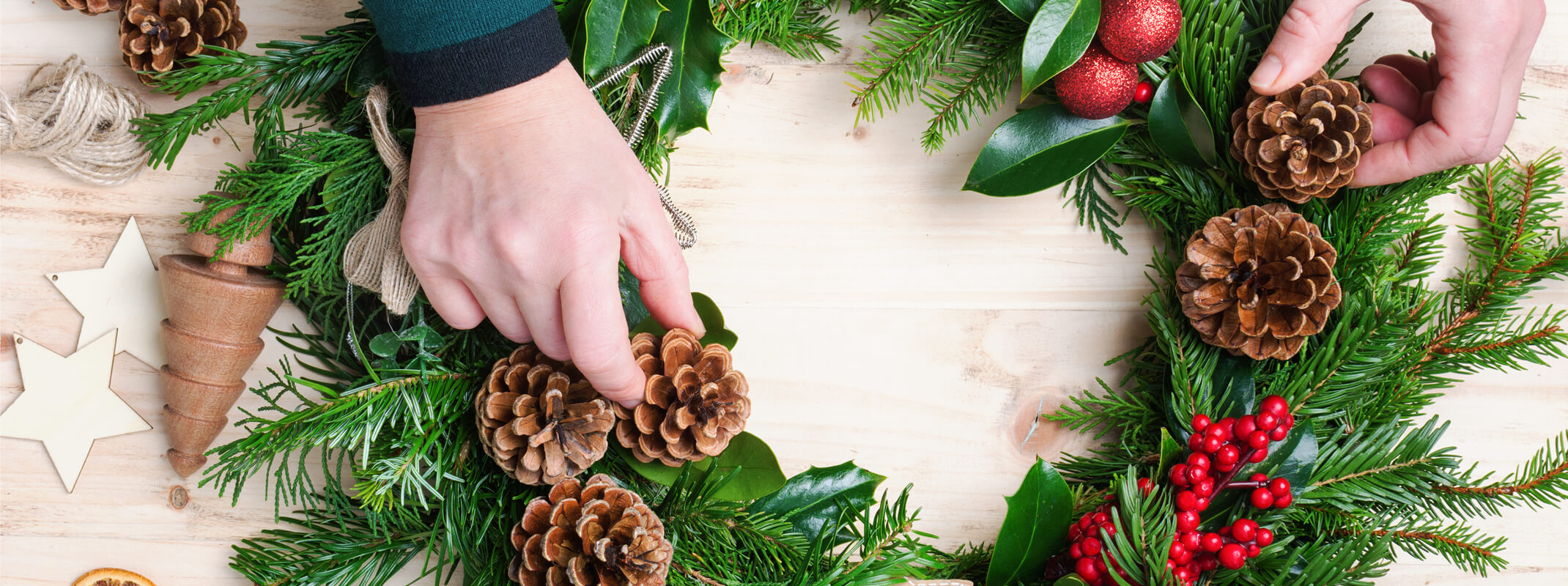 Assembling an evergreen holiday wreath with pinecones and berries