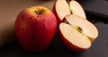 one whole and two halves of a honeycrisp apple on table