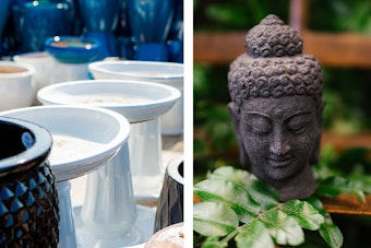 Birdbaths & Statues White bird baths near black and blue outdoor pottery, and a stone Buddha head surrounded by houseplants and wooden shelving