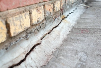 Crack along the foundation against a brick house.