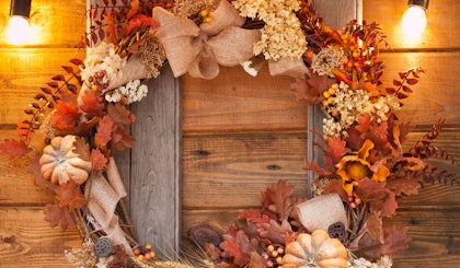 fall autumn wreath with leaves and pumpkins on wooden wall