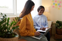 2 students studying in dorm room near houseplants.