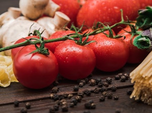 A row of Champion tomatoes on a wooden table with pasta, mushrooms and more...