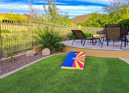 A lush winter lawn with a corn hole game on it and a patio nearby.