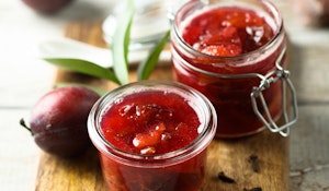 weeping santa rosa plum compte in jars with fresh fruit on board next to it