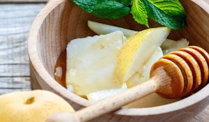 20th century asian pears sliced in wooden bowl with cheese and whole fruit in foreground